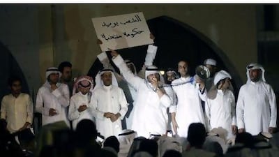 A Kuwaiti protester holds a banner reading "The people want an elected government" as another addresses fellow demonstrators outside the parliament building in Kuwait City late on June 10, 2011 during a rally demanding the resignation of the oil-rich Gulf state's Prime Minister Sheikh Nasser Mohammed al-Ahmed al-Sabah.