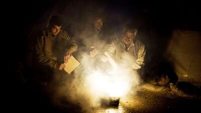Men heat a fire to boil water by their tent at a refugee camp near the Turkish border in Azaz, Syria. Manu Brabo / AP Photo