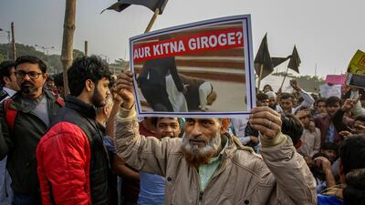 An Indian holds a poster that reads "How much lower will you fall?" during a protest rally against the Citizenship Amendment Act in Kolkata. AP