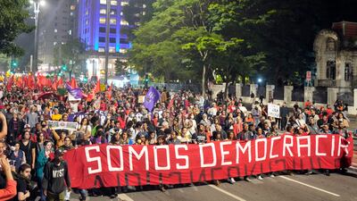 Demonstrators march holding a banner that reads in Portuguese: 'We are democracy.' AP