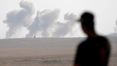 A member of Iraqi special forces looks on smoke rises over ISIL positions during heavy bombardment in Al Shura. Goran Tomasevic / Reuters