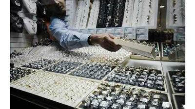 A salesman displays gold and diamond rings near the window in a jewellery shop at the Gold Souq in Dubai