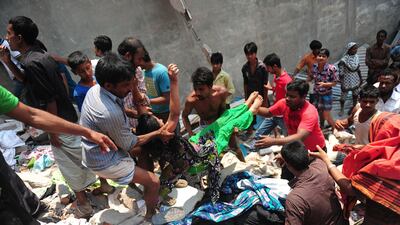 Bangladeshi garment workers help a survivor of the building collapse. AFP Photo / Munir uz Zaman