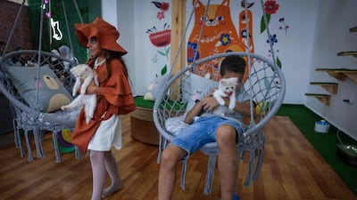 Children hold felines at the newly inaugurated Meow in Gaza City. AFP