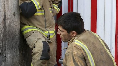 A firefighter sits next to his colleague on January 19, 2017, outside the historic Plasco building in Tehran, Iran. The iconic structure was destroyed by a fire on Thursday. Dozens of firefighters were killed when the building collapsed. Vahid Salemi / Associated Press