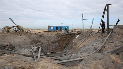 A Palestinian man walks past a crater on the ground in Khan Younis. AFP