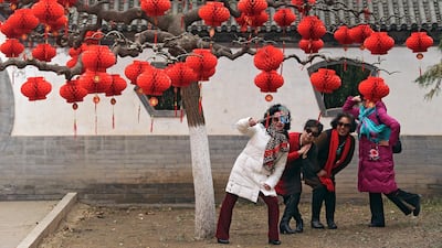 Chinese women take a selfie near a tree decorated with red lanterns. AP Photo