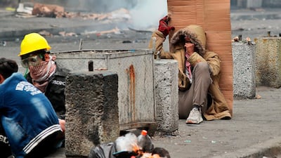 Anti-government protesters take cover during clashes with security forces in central Baghdad. AP Photo