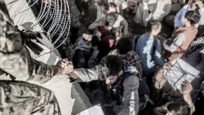 A US soldier helps a man over a barrier at Kabul airport during the withdrawal. Reuters