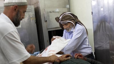 Sheik Ahmed Tarrouch, right, known as Abu Mohammed, prepares the body of Achmed Benasawi, 22, in the morgue at the Kamal Adwan Hospital in Beit Lahiya on July 18, 2014. Photo by Heidi Levine for The National