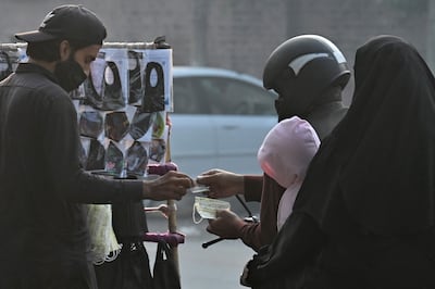 People buy face masks along a street amid smoggy conditions in Lahore on November 21, 2023. (Photo by Arif ALI / AFP)