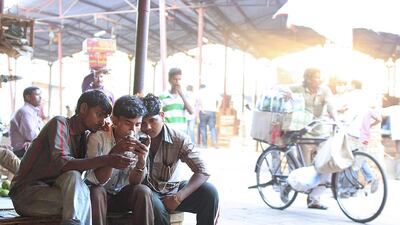 Porters relax and check their mobile phones while waiting for customers. Subhash Sharma for The National