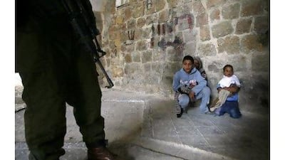 An Israeli soldier stands guard next to three Palestinian boys who were arrested for throwing stones during clashes in the West Bank city of Hebron. Hazem Bader / AFP Photo