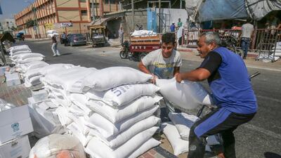 Palestinian men pile bags of flour outside an aid distribution centre run by the United Nations Relief and Works Agency (UNRWA) in the central Gaza Strip refugee camp of Bureij. AFP