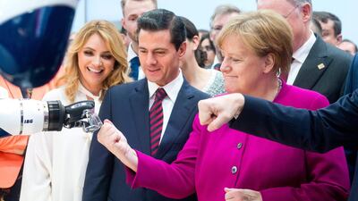 German chancellor Angela Merkel fist bumps a robot Mexican president Enrique Pena Nieto and his wife Angelica Rivera look on at the Hanover Fair in Hanover. Hauke-Christian Dittrich / dpa / AFP Photo