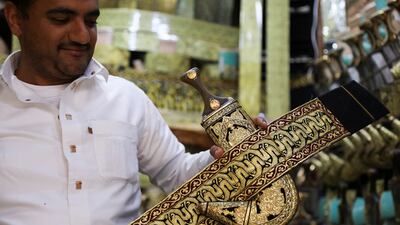 A vendor displays a Yemeni traditional dagger, or jambiya, with its belt made of metallic golden threads, at his shop in the old quarter of Sanaa, Yemen May 15, 2023. REUTERS / Khaled Abdullah