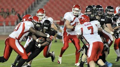 Abu Dhabi Wildcats running back Vivaldi Tulysse is tackled by two Dubai Stallions during the EAFL Desert Bowl on Friday night. Charles Crowell for The National / March 14, 2014