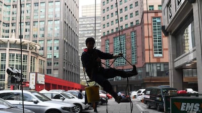 A window cleaner hangs from a rope as he descends after cleaning an office building in Beijing. Greg Baker / AFP