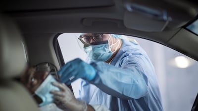 A nurse uses a nasal swab to test a driver at a Covid19 drive-through testing centre in Dubai. Mahmoud Khaled / EPA