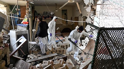 Forensic officials use metal detectors to inspect amid the debris of a damaged house after a gas cylinder explosion in a Christian colony in Islamabad. AFP