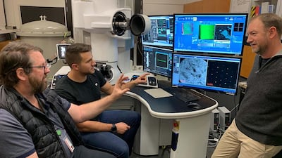 Prof Dougal McCulloch, left, Mr Salek from RMIT and Mr Tomkins from Monash, right, look at computer images of the meteor samples. Photo: RMIT University