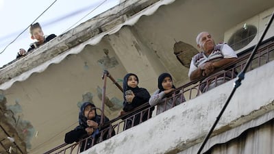 Residents stand on the balcony of their home near the scene of twin suicide bombings in Beirut's Burj Al Barajneh neighbourhood on November 13, 2015. Bilal Hussein, File/AP Photo