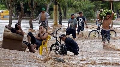 A youth carries bananas as he wades through a flooded street in El Progreso, department of Yoro, Honduras after the passage of Hurricane Iota. AFP