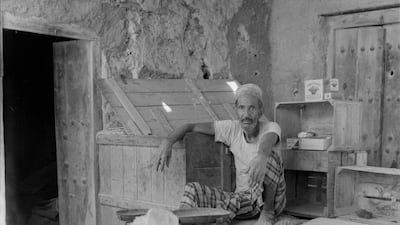 A trader sits amid bottles, crates and a scale in the Abu Dhabi souq in 1962. The Flower Basket matches visible on the right are still sold here.
