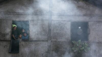 Rohingya look out from a window as smoke rises from people cooking over open fires at a school that is now a makeshift IDP camp November 24, 2012 on the outskirts of Sittwe, Myanmar. Paula Bronstein / Getty Images