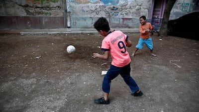 Children play with a ball at an alley between buildings.