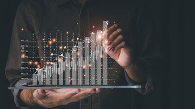 Businessmen are using tablet computers to analyse trends of fast-growing businesses with rising graph bars on a black background. Getty Images