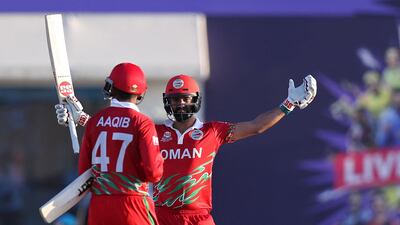 Oman's Jatinder Singh, right, and Aqib Ilyas celebrate their 10-wicket win over Papua New Guinea at the T20 World Cup first round match at the Oman Cricket Academy Ground in Muscat on Sunday, October 17, 2021. AFP