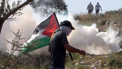 A Palestinian protester runs away from a tear gas canister fired by Israeli security forces during clashes in the village of Kfar Qaddum, near Nablus in the West Bank on Friday. Jaafar Ashtiyeh / AFP