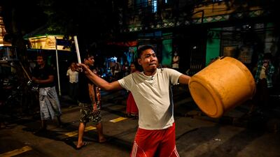 A man hits a plastic container to make noise after calls for protest went out on social media in Yangon, as Myanmar's ousted leader Aung San Suu Kyi was formally charged on Wednesday two days after she was detained in a military coup. AFP