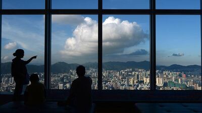 A woman points towards commercial and residential buildings in Hong Kong. Hong Kong lowered its annual economic forecast on August 15 after growth slowed to 1.8 per cent year-on-year in the second quarter. Dale De La Rey / AFP