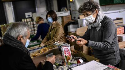A volunteer (R) of the charity 'Les Restos du Coeur' distributes food to a man in need at a centre of the charity in Paris on October 13. Christophe Archambault/ AFP