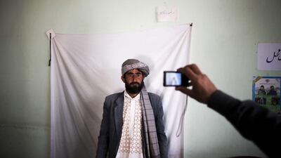 An Afghan election employee takes a picture of a resident to issue his voter card for the upcoming presidential election at a voter registration centre in the northwestern city of Herat. Behrouz Mehri / AFP