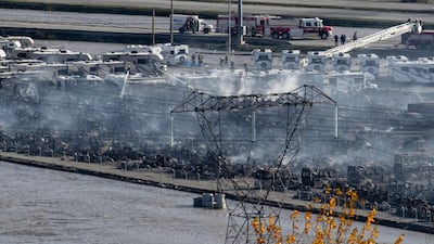 Firefighters direct water on hot spots after vehicles burned during a fire at a business surrounded by floodwaters in Abbotsford.