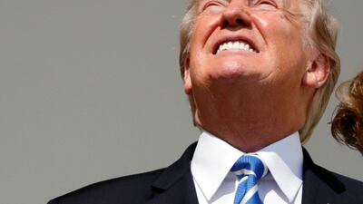 US president Donald Trump looks up towards the solar eclipse without his protective glasses on as he views the eclipse from the Truman balcony of the White House in Washington, US. Kevin Lamarque / Reuters