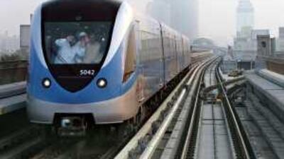 Passengers wave from a passing train on the Dubai Metro network. The Metro completes one month today.