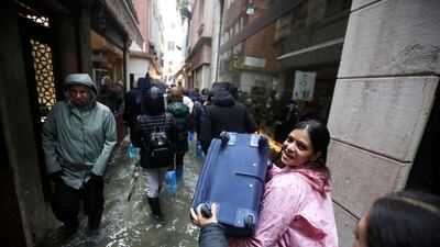 Tourists carry their luggage as they wade through water in a flooded Venice. AP