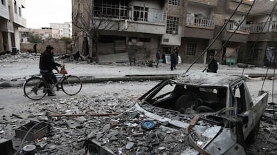 Syrians walk along a street covered in debris from shelling in Arbin in the rebel-held enclave of Eastern Ghouta on February 25, 2018. Bdulmonam Eassa / AFP