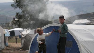 Internally displaced Syrian boys stand near tents in Azaz, Syria. REUTERS