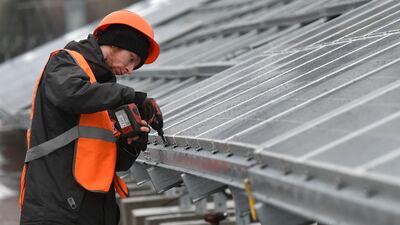 A worker installs photovoltaic panels on the new one-megawatt power plant next to the New Safe Confinement over the fourth block of the Chernobyl nuclear plant on December 12, 2017. Genya Savilov / AFP