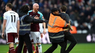 A pitch invader is seized by security staff during the English Premier League match between Burnley and West Ham at the Olympic London Stadium in London. Daniel Hambury / PA via AP