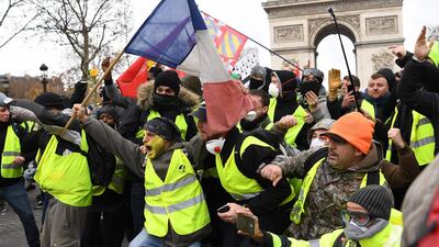 TOPSHOT - Protestors wearing "yellow vest" (gilet jaune) gesture on December 8, 2018 near the Arc de Triomphe in Paris during a protest against rising costs of living they blame on high taxes. Paris was on high alert on December 8 with major security measures in place ahead of fresh "yellow vest" protests which authorities fear could turn violent for a second weekend in a row. / AFP / Eric FEFERBERG