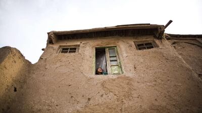 An Afghan girl smiles as she looks through a window of her house in the old part of the northwestern city of Herat. Behrouz Mehri / AFP