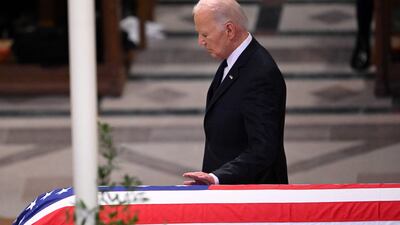 Mr Biden touches the coffin. AFP