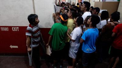 Voters look for their names posted on a bulletin inside a school polling precinct during the national elections at Manila in the Philippines. Czar Dancel / Reuters