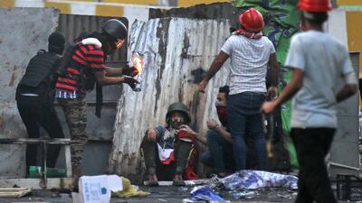 An Iraqi protester lights a Molotov cocktail as his comrades take cover behind a barricade amid clashes with security forces at Baghdad's Khallani square during ongoing anti-government demonstrations. AFP